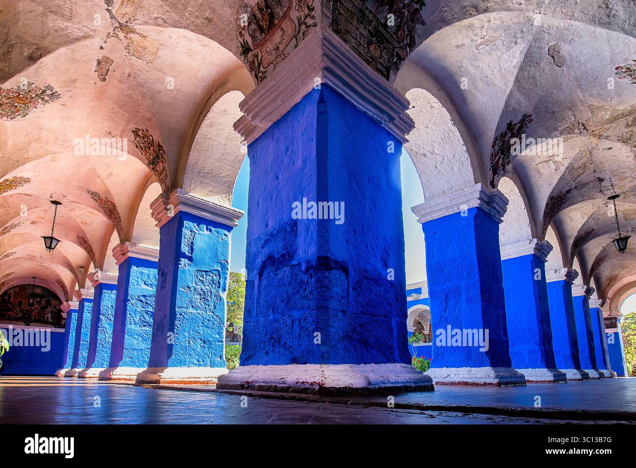 Vista delle vivaci colonne blu che sostengono soffitti ad arco adornati da affreschi sbiaditi, che creano un ritmo visivo accattivante, Arequipa, Arequipa, Perù. Foto Stock