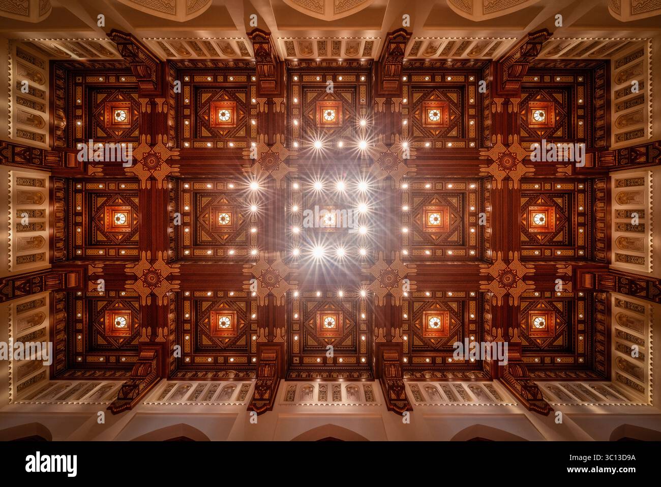 Mascate, Oman - 12 aprile 2022: Vista del soffitto squisitamente lavorato, che mostra intricati motivi geometrici e una luce calda e invitante che danzano sul legno scuro e sull'intonaco pallido. Foto Stock