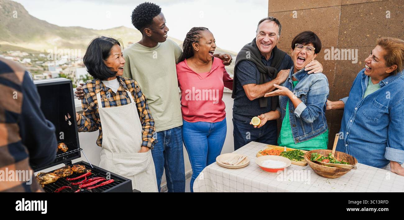 Persone multigenerazionali che fanno barbecue sul tetto di casa - amici multirazziali che si divertono a mangiare e cucinare insieme durante il fine settimana Foto Stock
