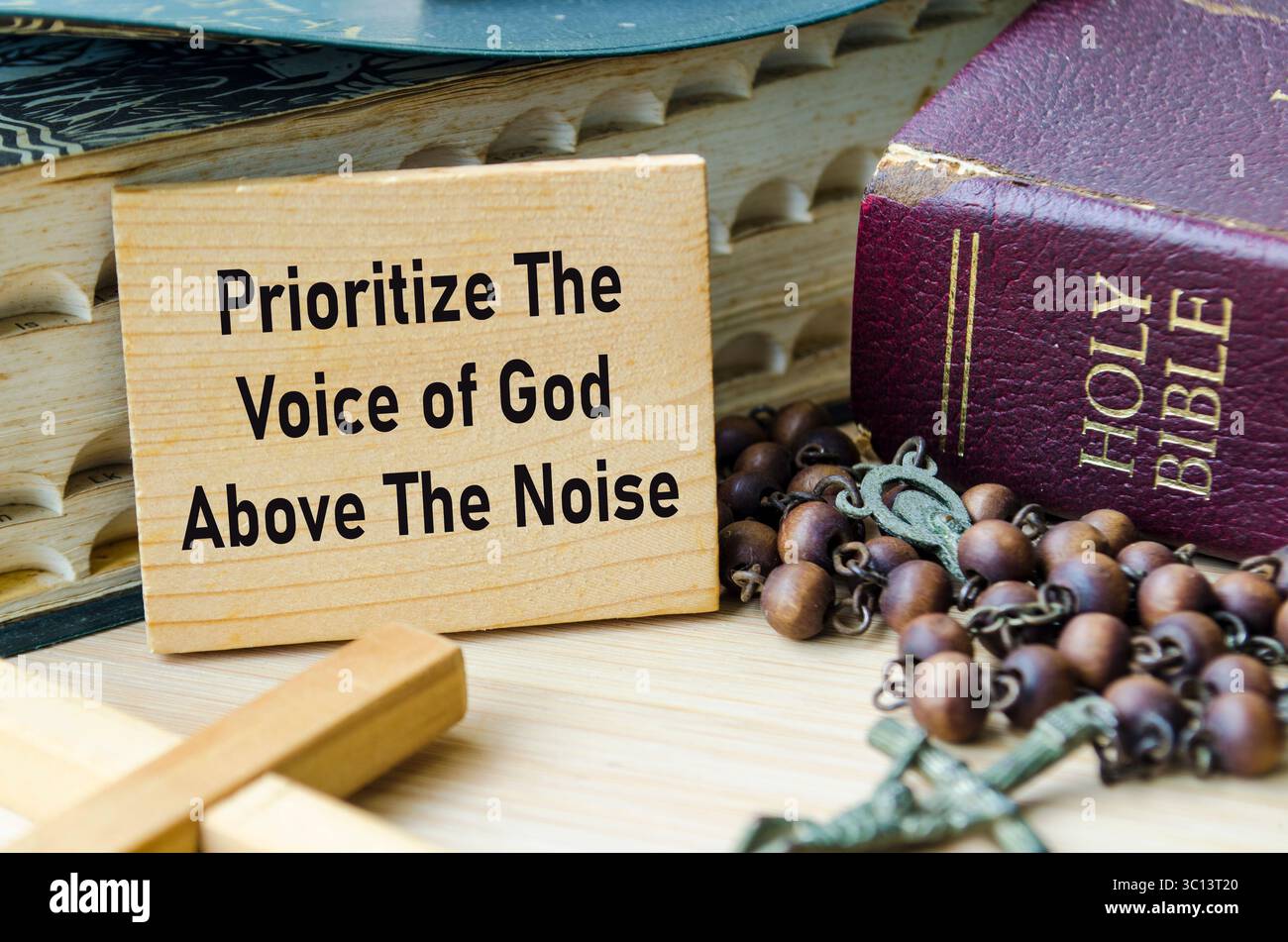 Dare priorità alla voce di Dio sopra il testo del rumore su un blocco di legno con sfondo Sacro Rosario e Sacro Bibbia. Concetto di cristianesimo. Foto Stock