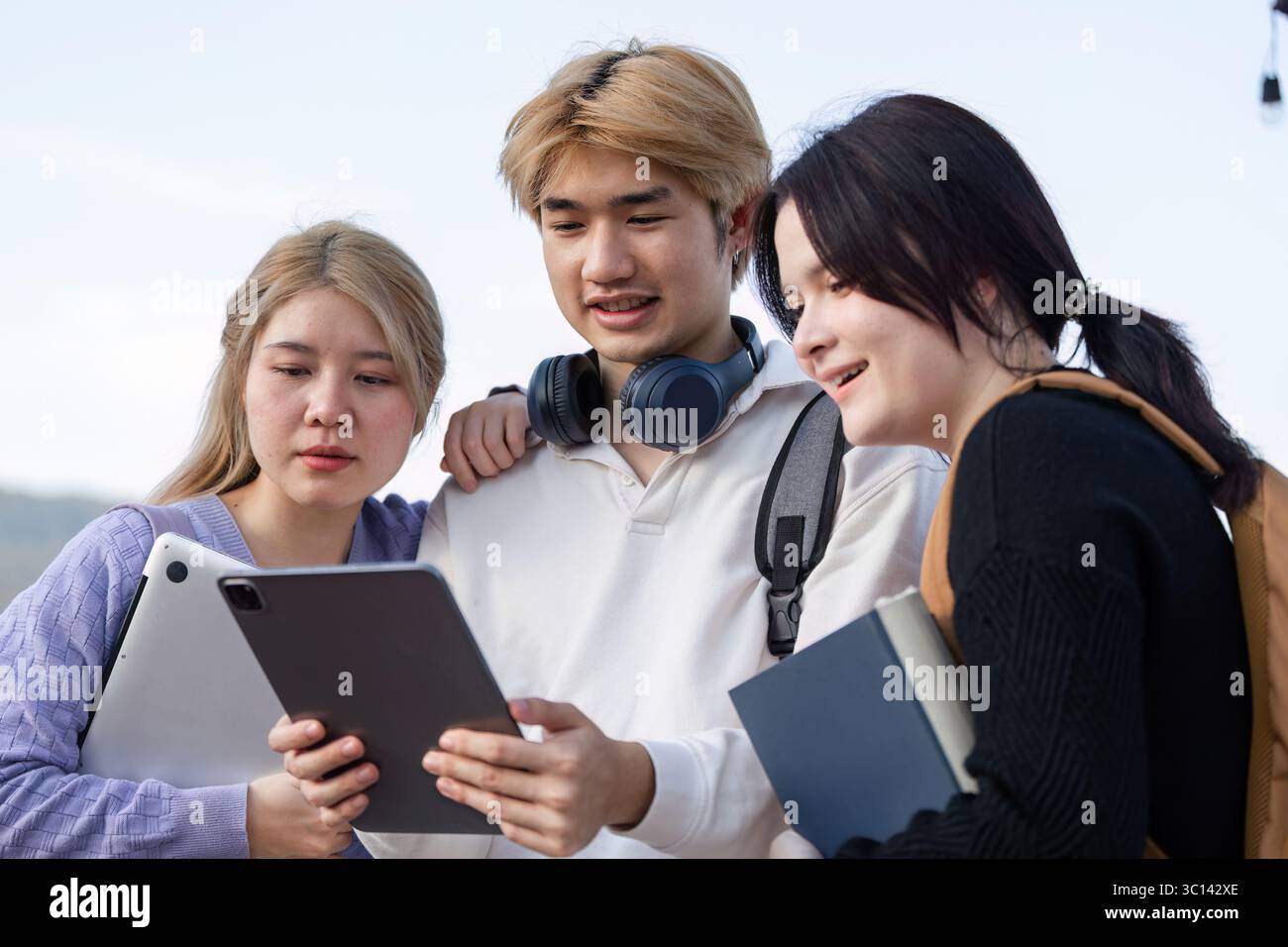 Diversi gruppi di studenti impegnati nell'apprendimento online all'aperto con notebook e tablet Foto Stock