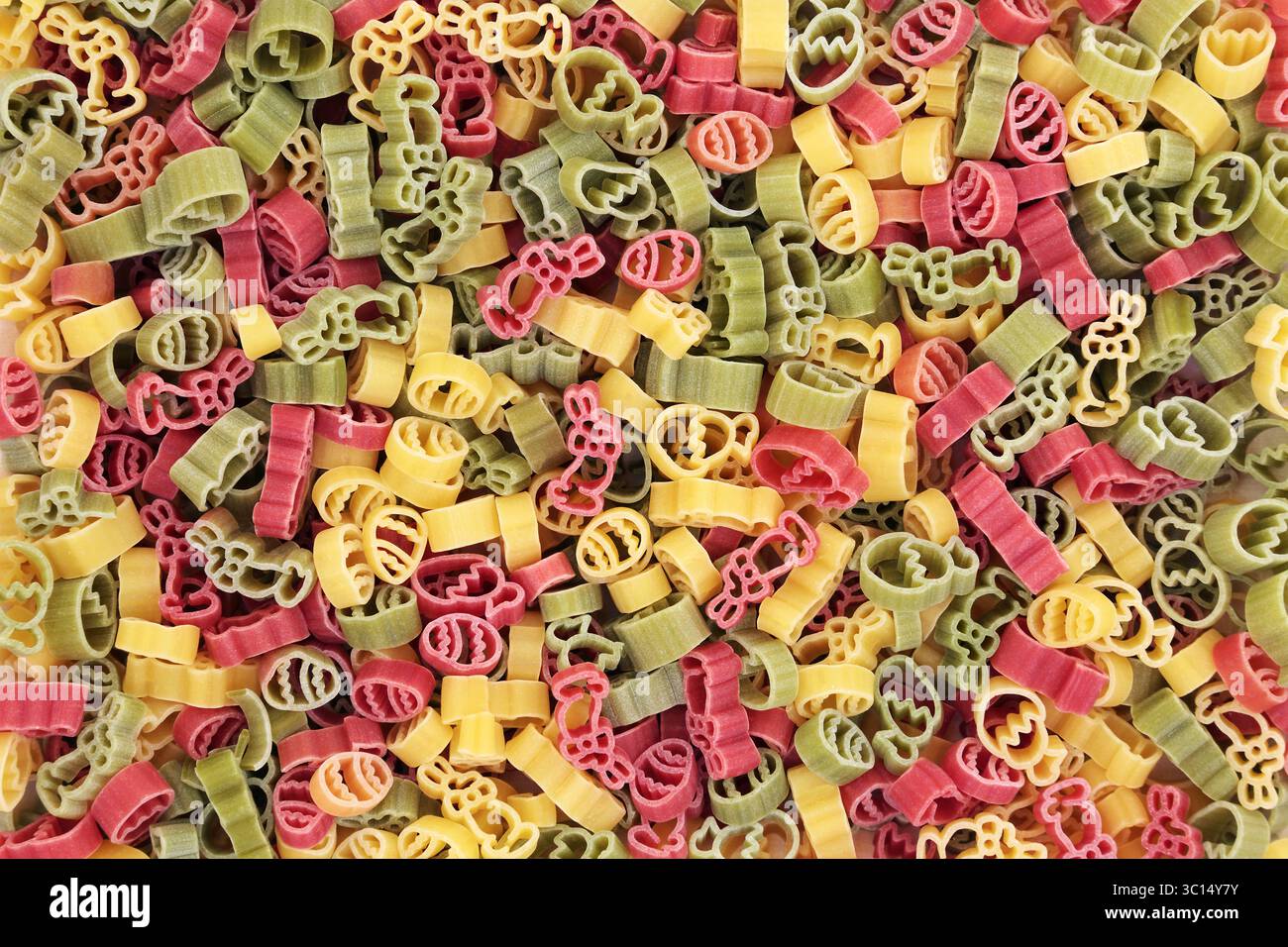 Pasta secca tricolore italiana con sfondo a tema pasquale di uova, coniglio coniglio e fiori di tulipano nei colori rosso verde e giallo. Foto Stock