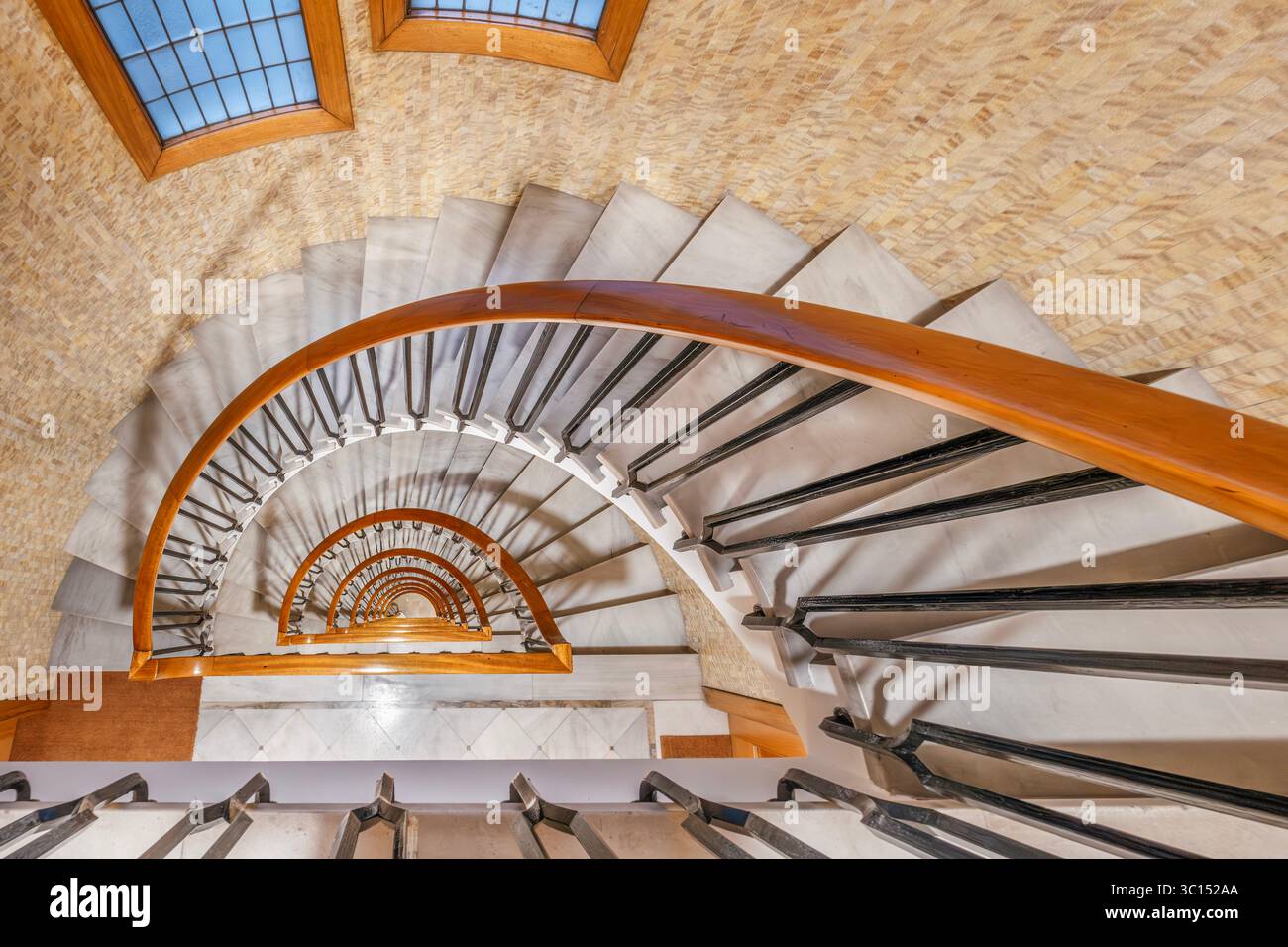 Vista astratta della scala a spirale dall'alto, elegante design architettonico. Ripetizione, forme geometriche, prospettiva interna Foto Stock