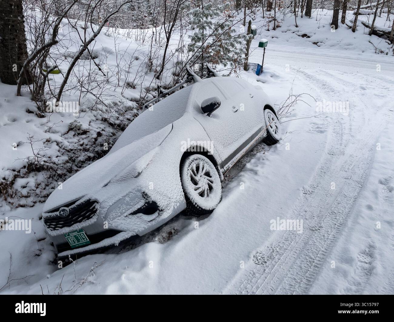 Un carro attrezzi si prepara a tirare un'auto fuori da un fossato in un vialetto innevato nel Vermont, New England, Stati Uniti. Foto Stock