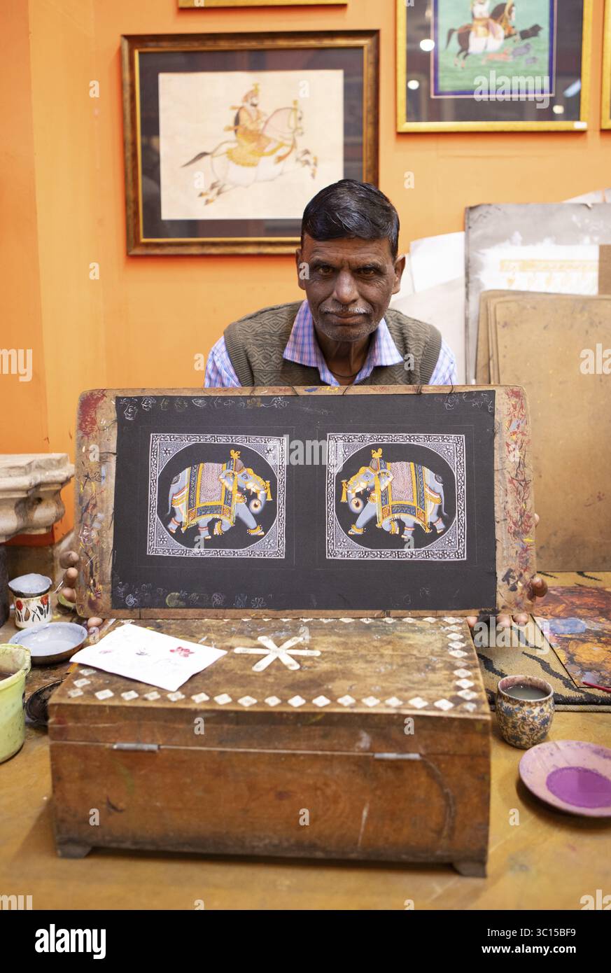 Il pittore in miniatura, 52 anni, mostra un'immagine dell'elefante reale nel suo studio, Udaipur, Rajasthan, India Foto Stock