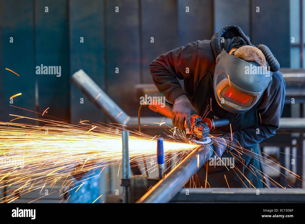 Germania - foto a tema: Industria metallurgica. Un lavoratore industriale taglia un tubo in acciaio con una smerigliatrice angolare. Foto Stock