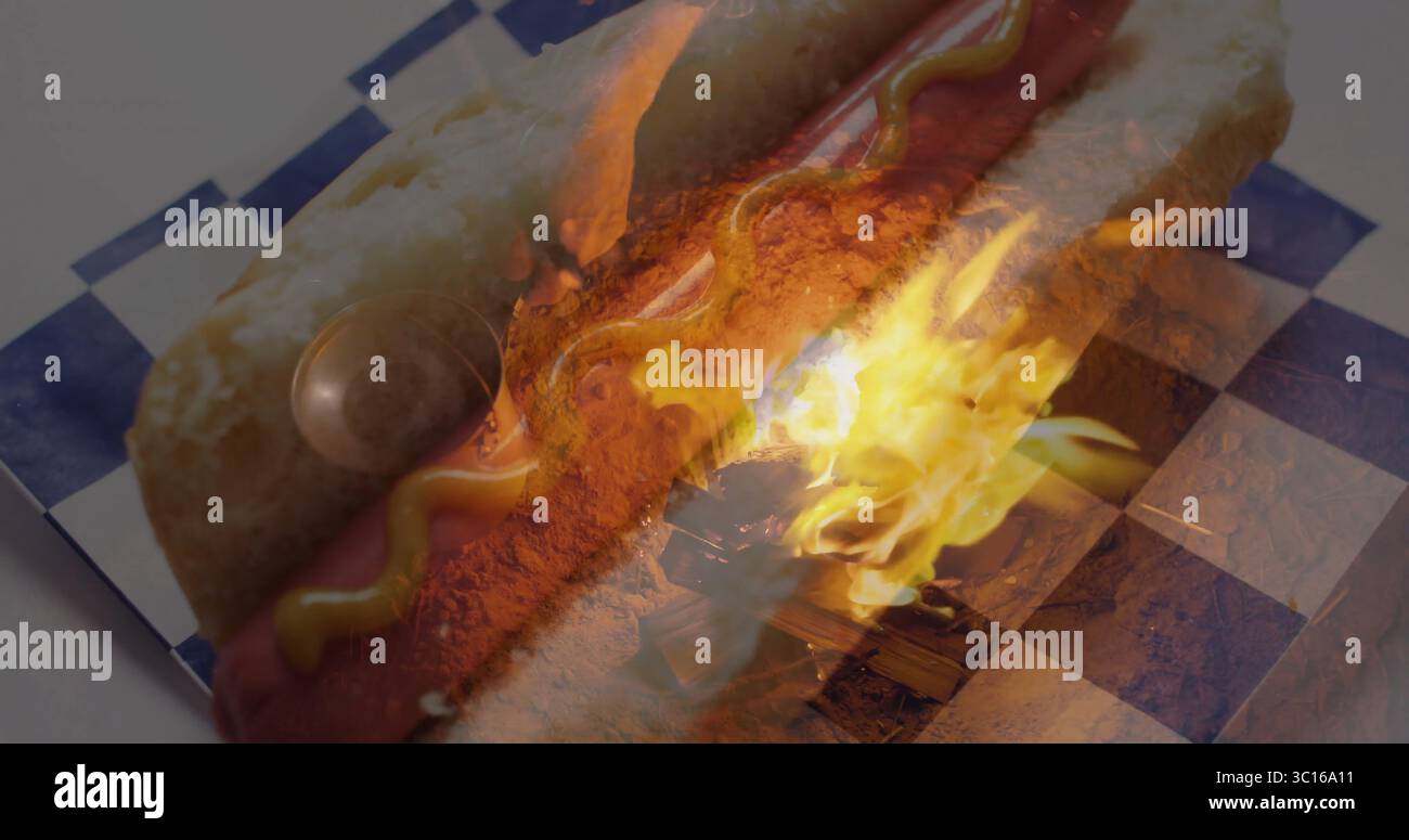 Con hotdog con linea di senape su carta a scacchi blu bianca al tavolo della cucina con fiamma Foto Stock