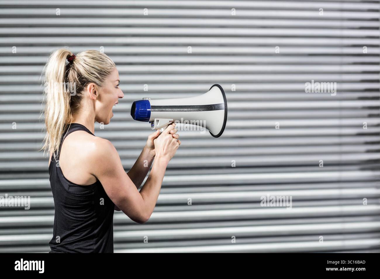 Megafono bianco e blu appoggiato allo sportello della serranda a rullo in metallo ondulato all'ingresso del magazzino Foto Stock