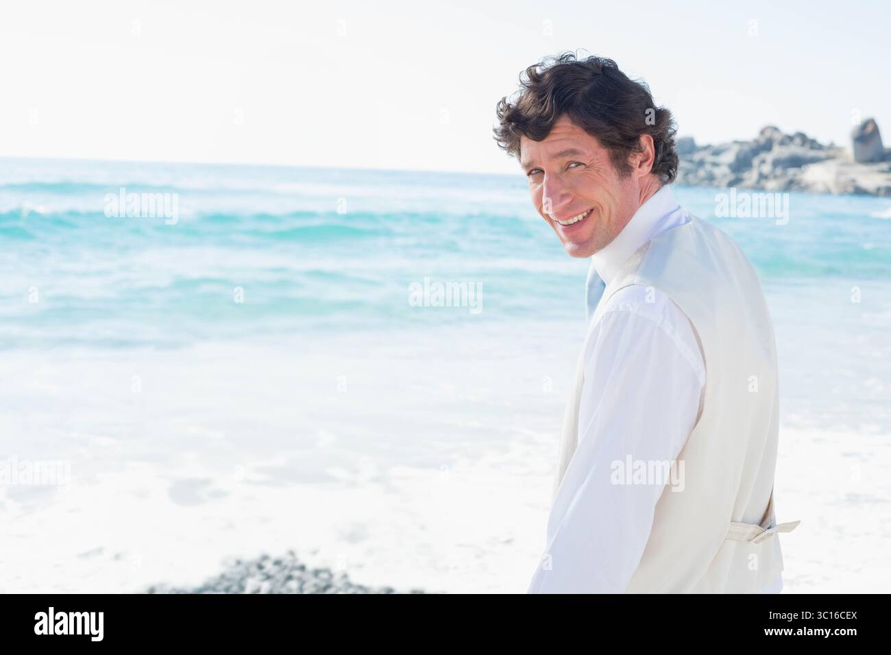Uomo che indossa una camicia bianca e un gilet beige in piedi sulla costa rocciosa, copia spazio Foto Stock