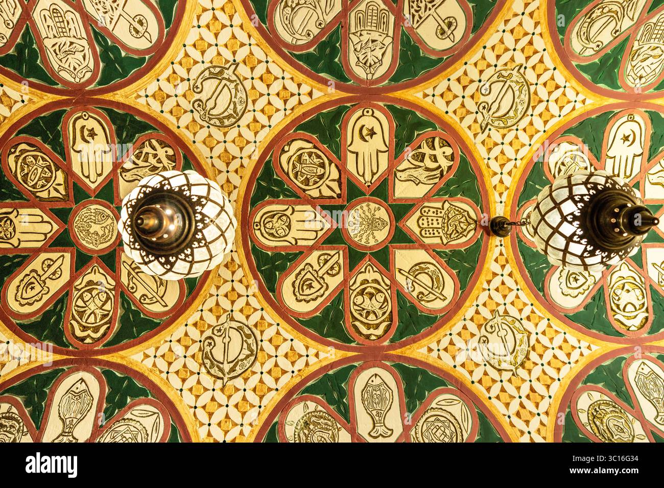 Un primo piano di un tradizionale soffitto tunisino splendidamente decorato, adornato con motivi geometrici colorati e simbolico motivo hamsa (mano di Fatima) Foto Stock