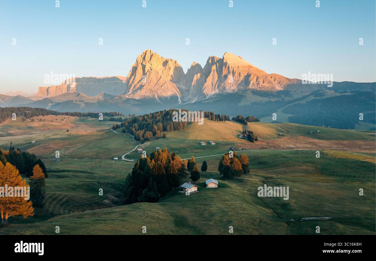 Vista aerea della maestosa catena montuosa del Sassolungo immersa nel caldo bagliore dell'alba sui verdi prati ondulati, Busto Arsizio, Lombardia, Italia. Foto Stock