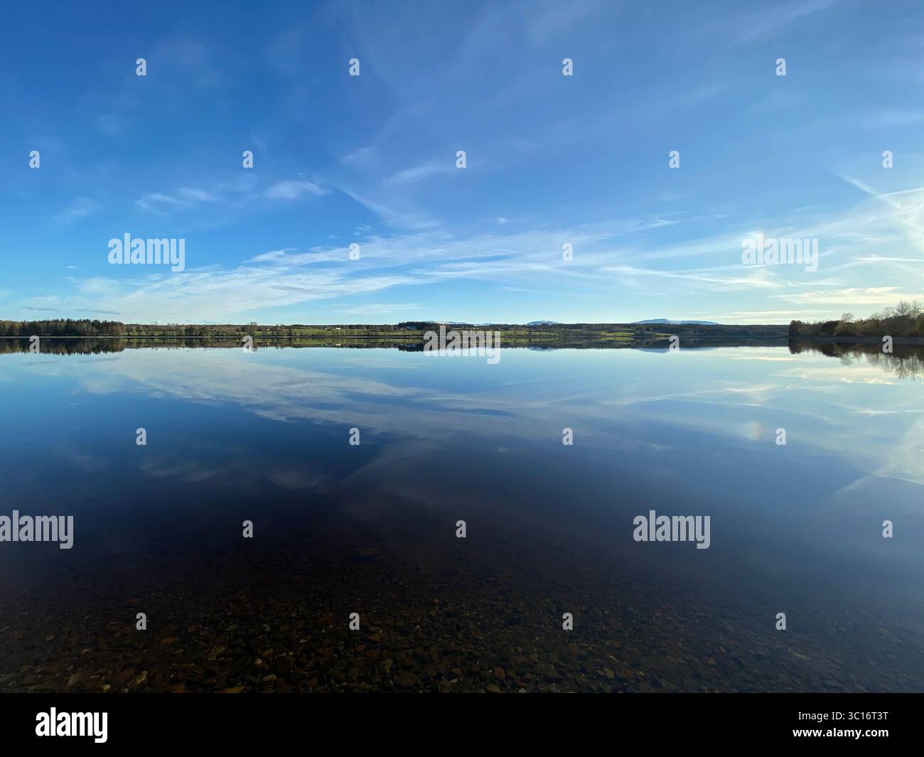 Il tranquillo lago riflette perfettamente lo splendido cielo blu e le soffici nuvole. - Immagine stock catturata con smartphone