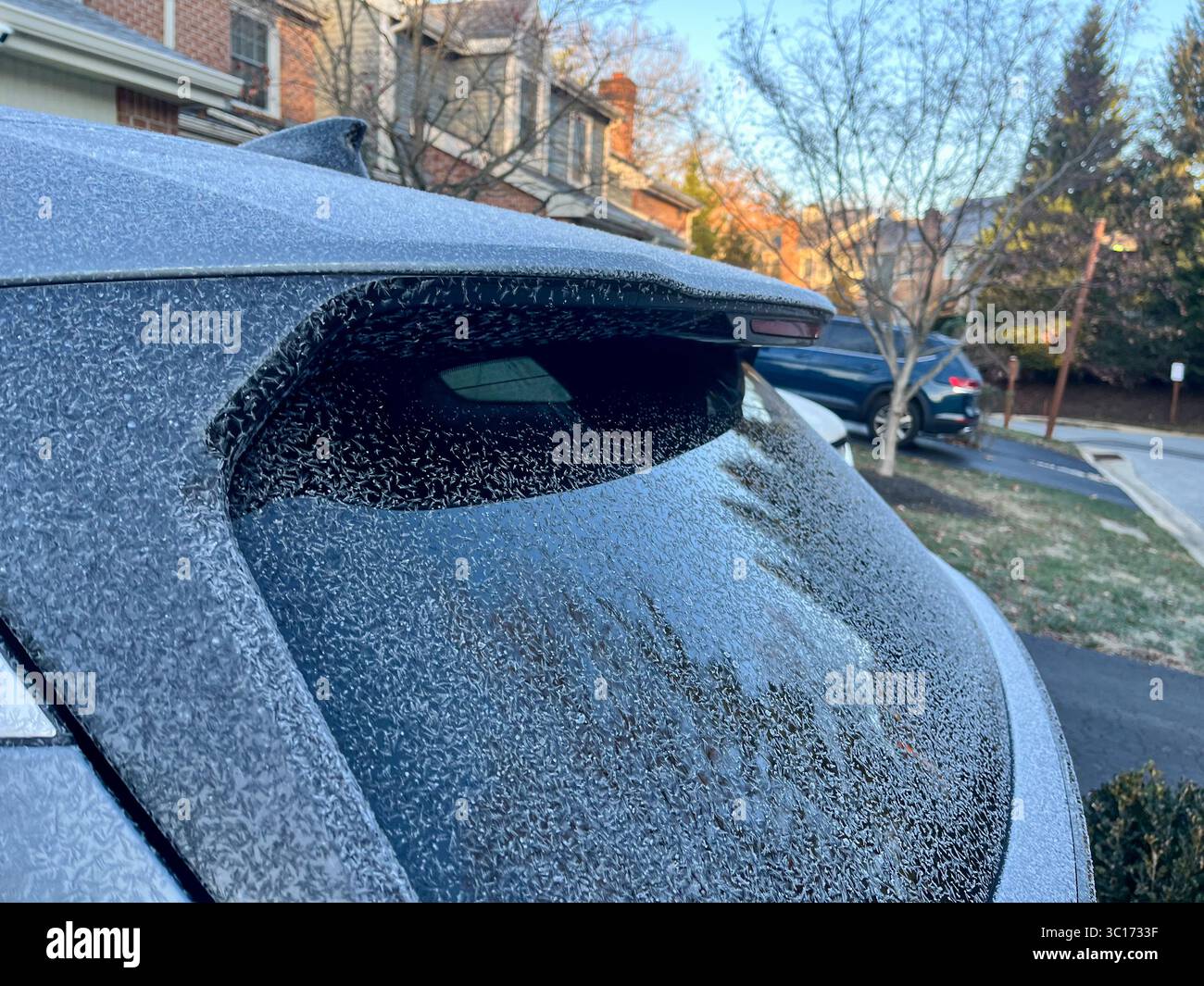 Un'auto con un finestrino posteriore smerigliato si trova in un vialetto. L'auto è parcheggiata accanto a una casa con un camino Foto Stock Un'auto con un finestrino posteriore smerigliato si trova in un vialetto. L'auto è parcheggiata accanto a una casa con un camino Foto Stock