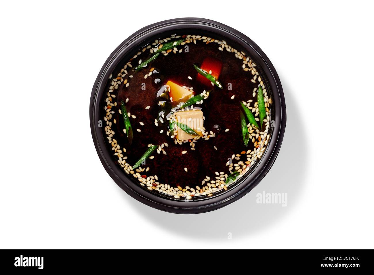 Zuppa di miso con tofu, alghe wakame, cipolle verdi e semi di sesamo in una ciotola nera Foto Stock