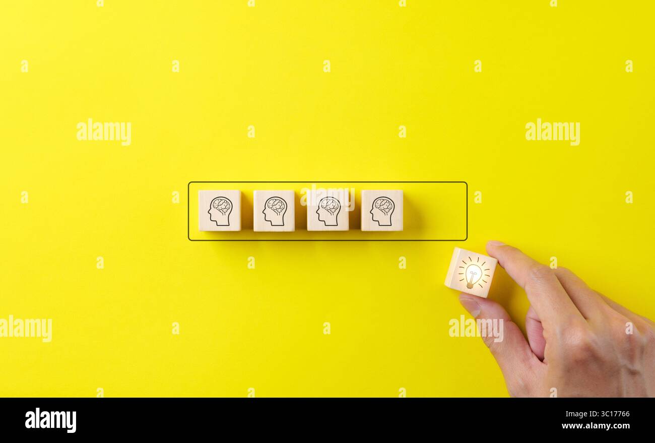Idea creativa e concetto di innovazione della conoscenza. La mano mette insieme blocchi di legno, cubo con l'icona della lampadina e vari umani su sfondo giallo. Foto Stock