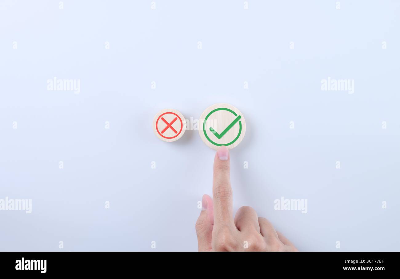 Approvare e rifiutare il concetto di proposta aziendale. Mano scegliendo l'icona destra su sfondo bianco. Simbolo vero e falso su blocco di legno, segno di spunta, segno x s Foto Stock