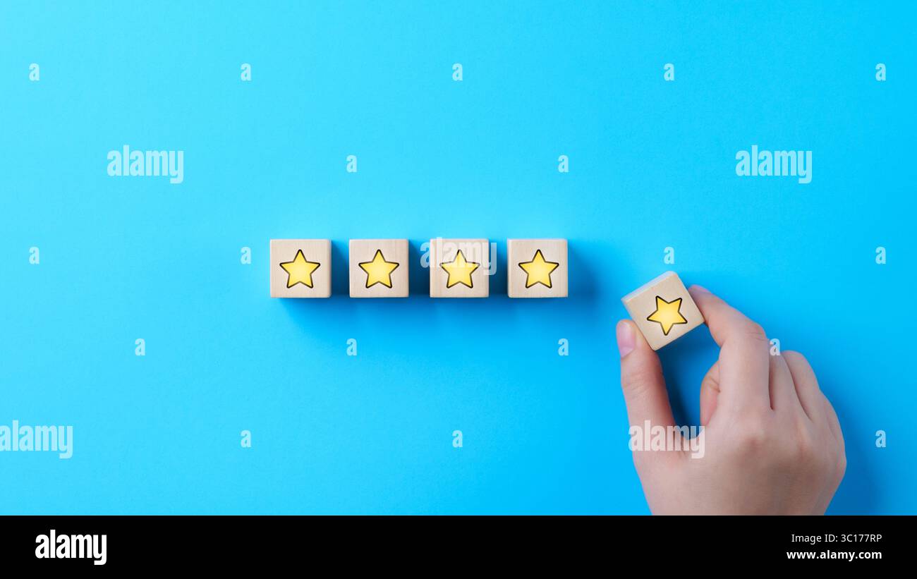 Analisi dei clienti feedback sulla soddisfazione del cliente. Mettere a mano un blocco cubico di legno con l'icona a stella gialla su sfondo blu. Questionario clienti, Servi Foto Stock