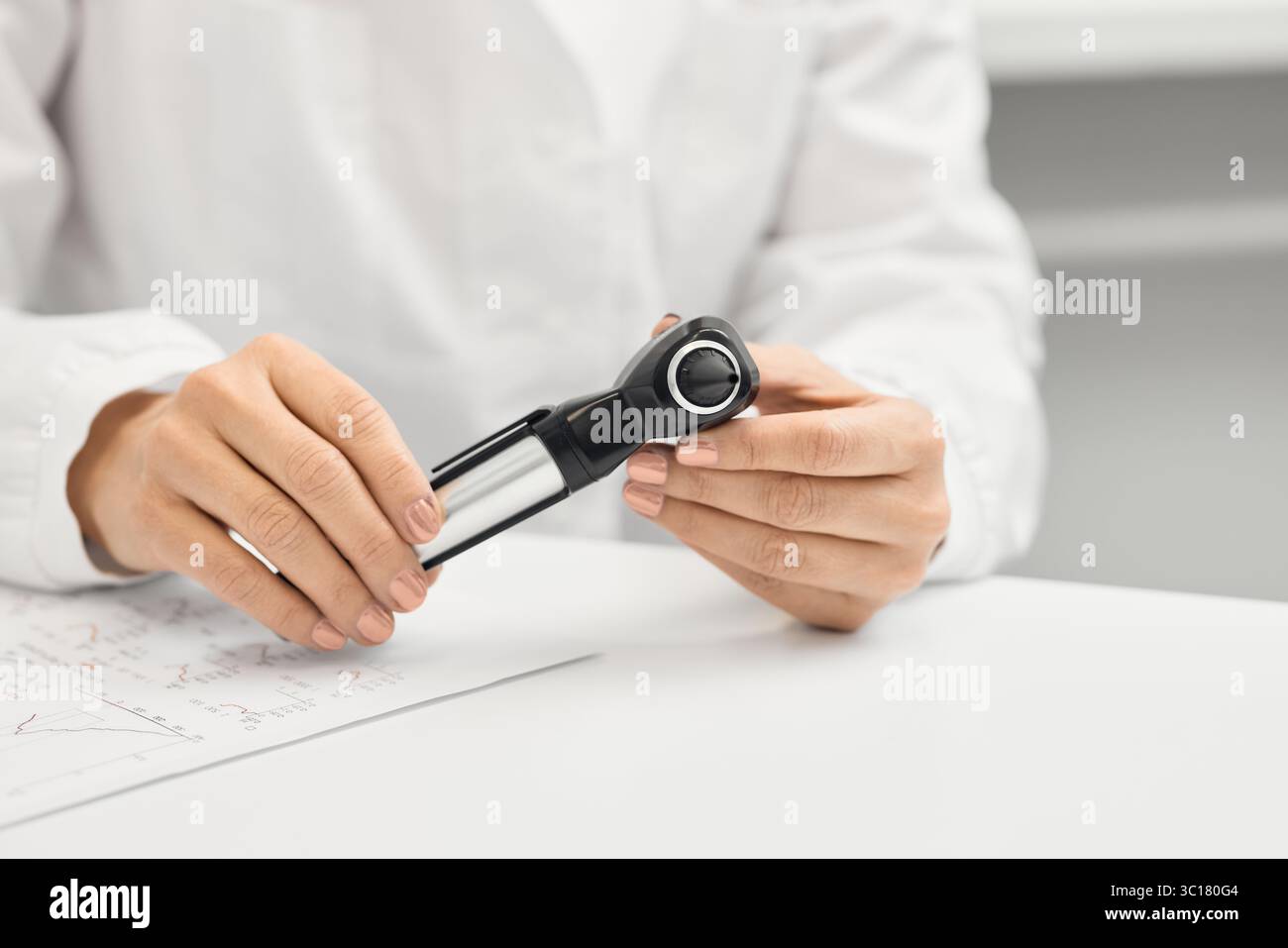 Consulenza audiologa, trattamento sordità. Medico ENT con otoscopio in mani seduto nel suo ufficio audiologico durante la sua consultazione Foto Stock