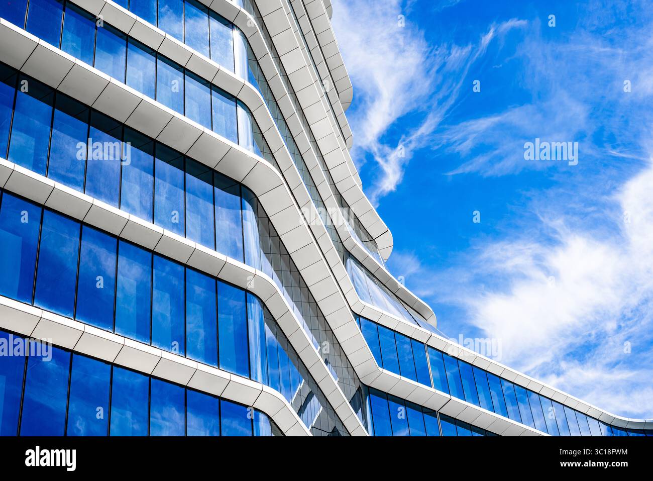 Moderno edificio residenziale a più piani con facciata vivace, grandi balconi e skyline urbano sotto il cielo azzurro Foto Stock
