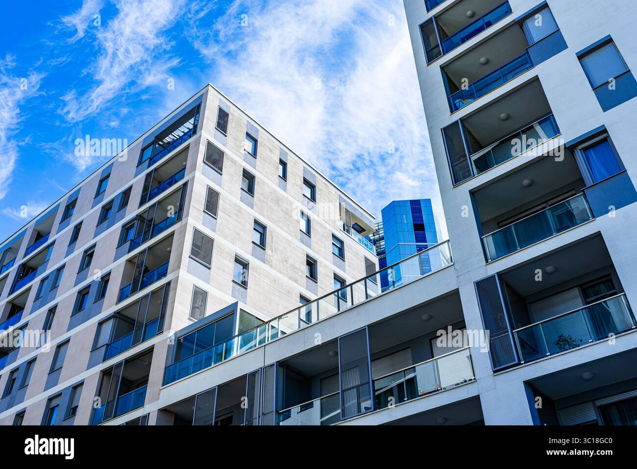 Moderno edificio residenziale a più piani con facciata vivace, grandi balconi e skyline urbano sotto il cielo azzurro Foto Stock