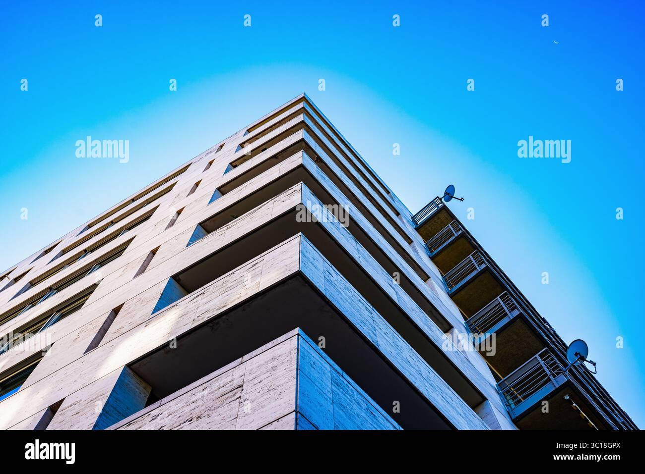 Prospettiva verticale di un edificio moderno con finestre riflettenti contro un cielo blu chiaro Foto Stock