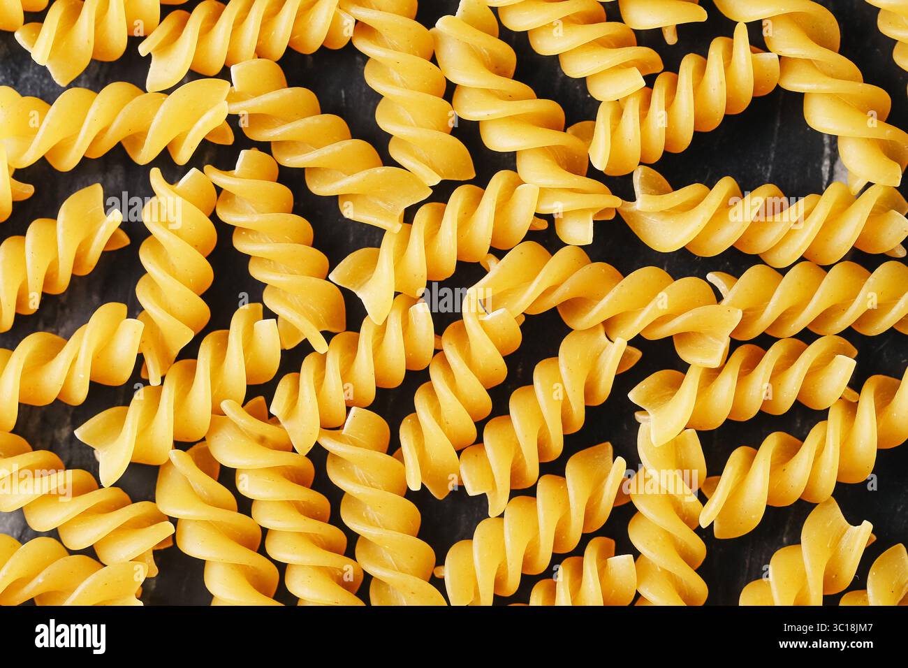Fondo di pasta fusilli gialla. Primo piano degli spaghetti a spirale crudi. Consistenza di cibo crudo italiano. Dettagli superficie macaroni asciutti. Ingrediente tradizionale. Foto Stock