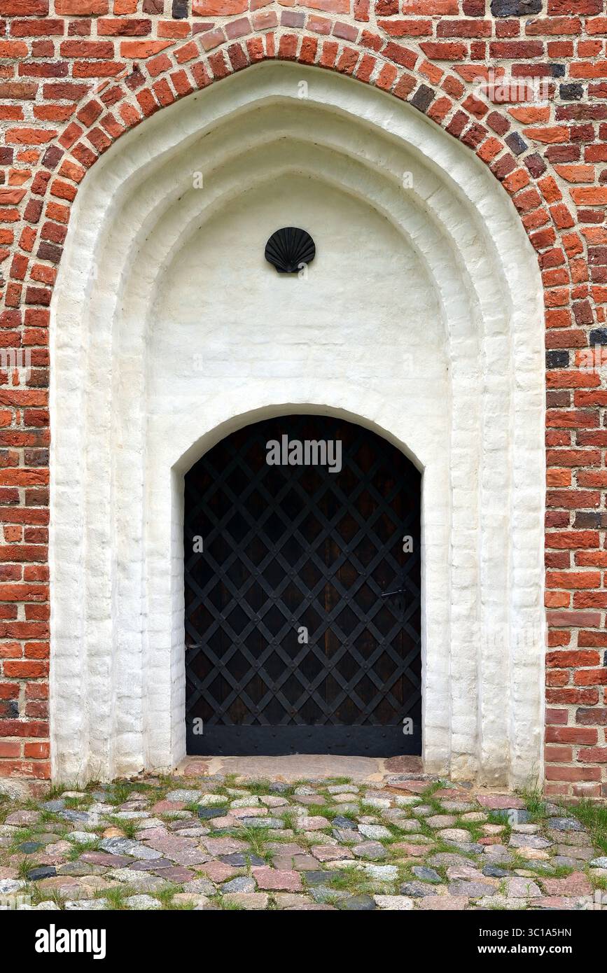Storico portale ad arco a punta con rilievo a conchiglia e porta a reticolo Foto Stock