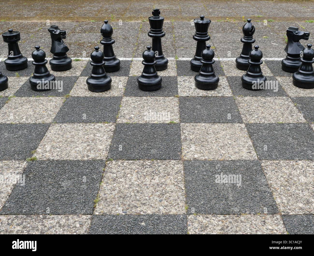 Partita a scacchi all'aperto con pezzi neri su una tavola bianca e nera. Copyspace Foto Stock