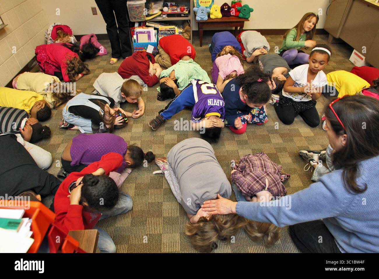 19 aprile 2012 - Spring Lake Park, Minnesota, Stati Uniti - nell'ambito della settimana di sensibilizzazione sulle condizioni atmosferiche gravi, anche le scuole di tutto lo stato stanno conducendo esercitazioni preparano gli studenti ai pericoli di un tornado diretto che colpisce la loro scuola. Oltre 350 studenti dall'asilo alla terza elementare della Park Terrace Elementary School di Spring Lake Park si sono riuniti in uffici di facoltà nel nucleo interno della scuola per praticare le procedure ''anatra e copertura'' da utilizzare in una reale emergenza. L'insegnante sostituto Gayle Middlecamp, giusto, ha aiutato gli studenti ad assumere la posizione di "anatra e copertura". (Immagine di credito: Marlin Levison/Minneapoli Foto Stock
