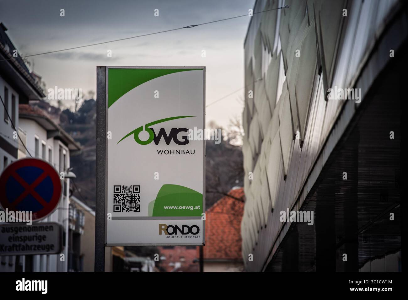GRAZ, AUSTRIA - 17 DICEMBRE 2024: Il logo della cooperativa OWG Wohnbau si erge accanto al complesso Rondo di Graz, è un costruttore austriaco di case in gr Foto Stock
