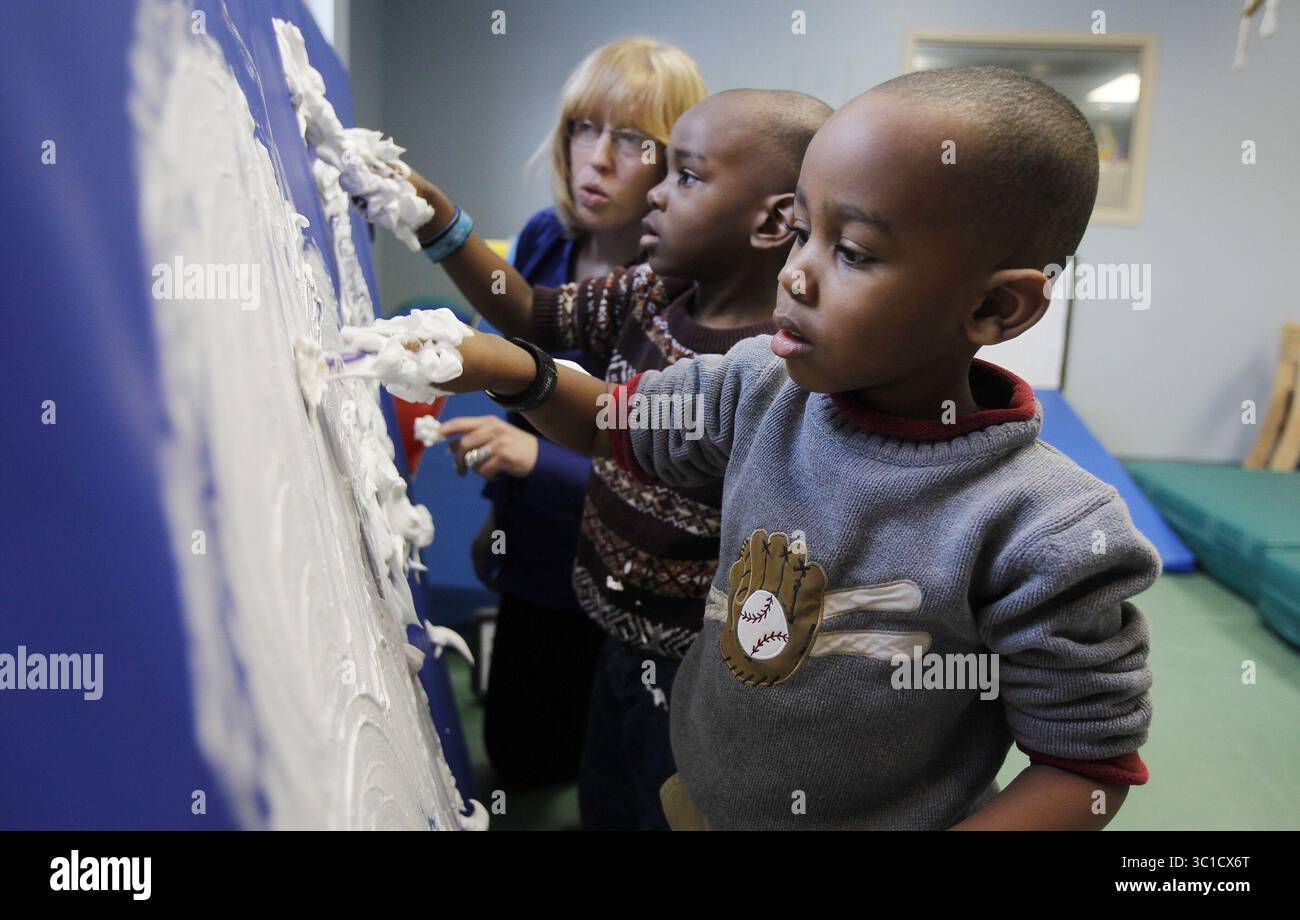 11 febbraio 2011 - Stati Uniti - Ã¢â‚¬Â¢ Minneapolis, MN 03/21/2011----- Alexander e Jrawin Fernandez hanno per i ragazzi che vengono curati al Fraser Child & Family Center di Minneapolis, uno dei più grandi programmi per bambini autistici del Minnesota.-- IN QUESTA FOTO Elisa Roiko Right un terapista aiuta i gemelli Elijah (al centro) e Seth 4, Fernandez mentre lavoravano con la crema da barba. La crema aiuta i bambini con sensibilità. (Immagine di credito: Jerry Holt/Minneapolis Star Tribune/TNS via cavo ZUMA) Foto Stock