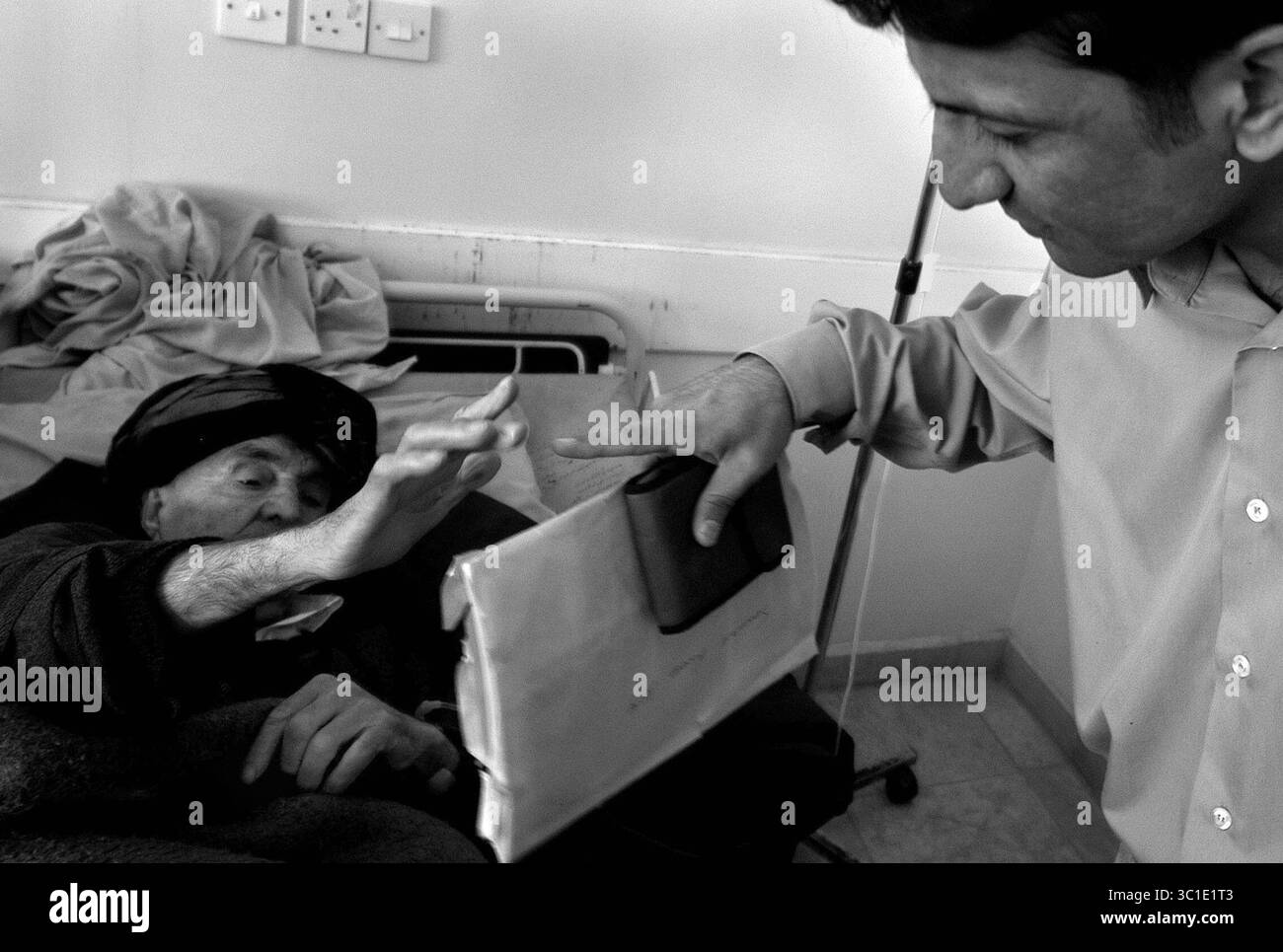 25 febbraio 2003 - Halabja, Iraq - quasi 15 anni dopo essere stato bombardato da gas velenosi e agenti nervosi provenienti da aerei da guerra iracheni migliaia di residenti di Halabja affrontano quotidianamente gravi problemi di salute fisica e psicologica. Il dottor BAKHTIAR FAIQ raggiunge e tocca un paziente che soffre di depressione. Il dottor Faiq gioca a questo gioco con i pazienti per vedere se riescono a toccare il dito. La depressione è uno dei sintomi principali che affliggono i sopravvissuti di Halabja. (Immagine di credito: Richard Sennott/Minneapolis Star Tribune/TNS via cavo ZUMA) Foto Stock