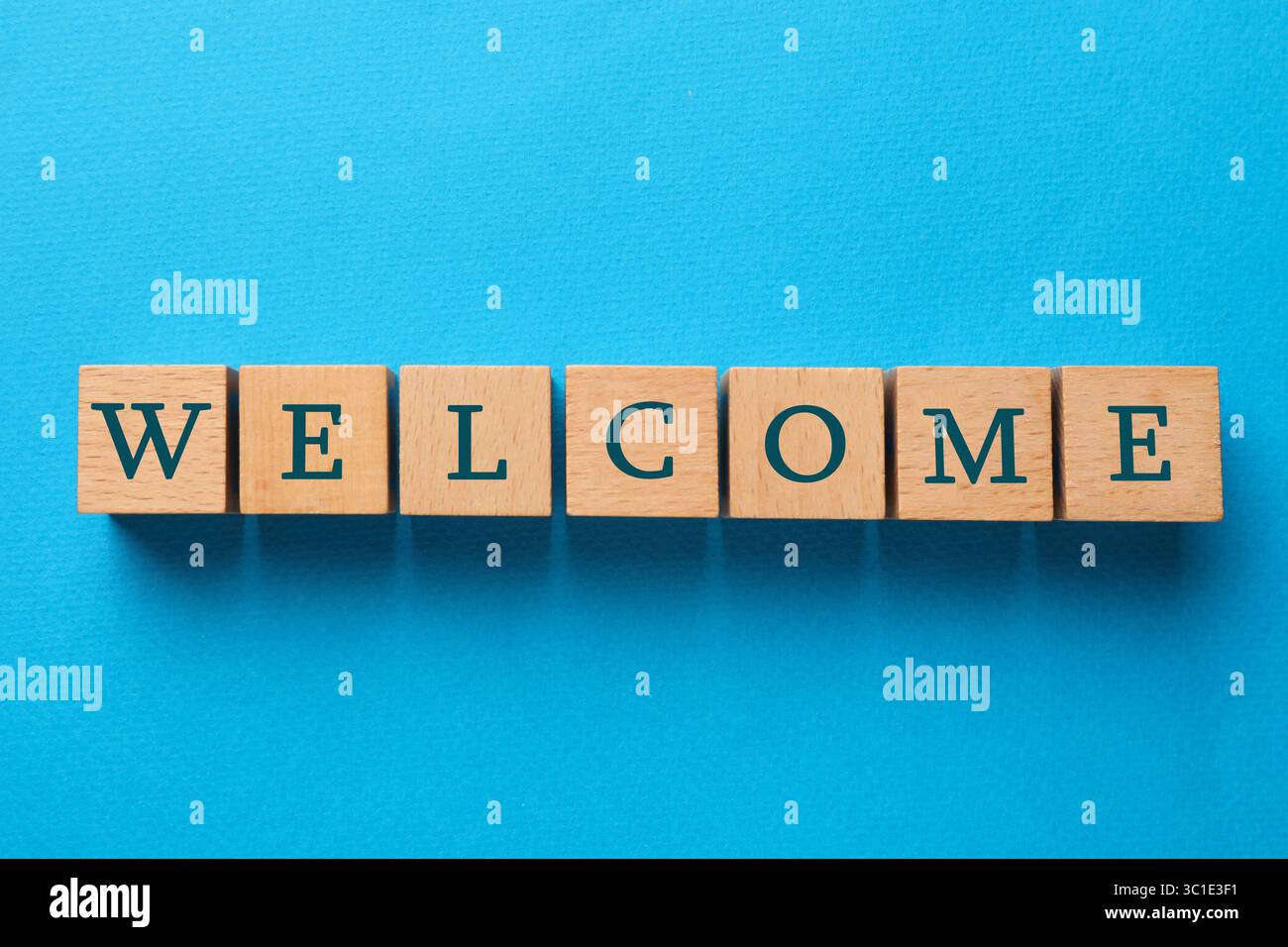 Parola di benvenuto: Cubi di legno su sfondo azzurro, vista dall'alto Foto Stock