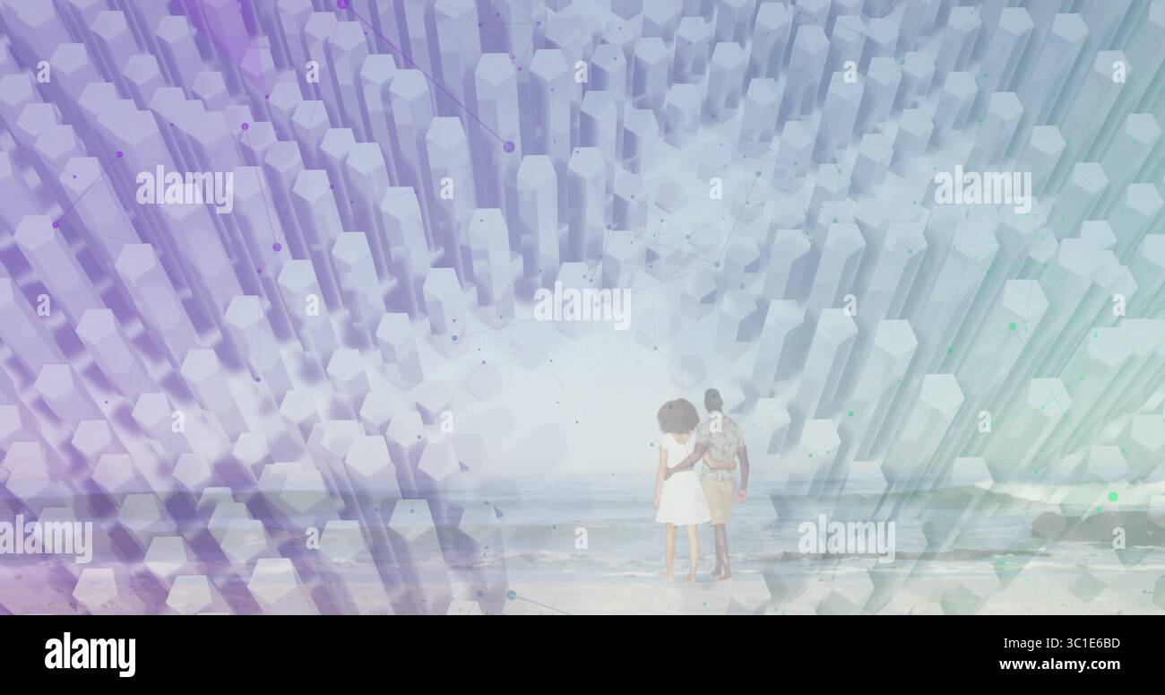 Coppia in piedi che indossa un abito bianco e una camicia stampata di fronte all'acqua in spiaggia, colonne chiare che si innalzano Foto Stock