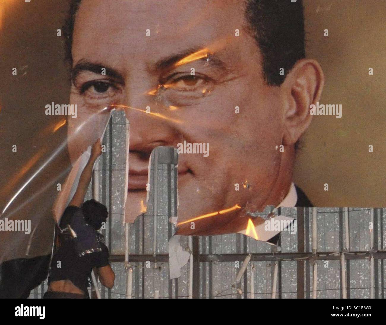 25 gennaio 2011 - Alexandria, EGY - RI-TRANS PER COLTURA ALTERNATIVA Un manifestante scompare un manifesto del presidente egiziano Hosni Mubarak ad Alessandria, Egitto, martedì 25 gennaio 2011. Migliaia di manifestanti hanno marciato ad Alessandria martedì in quello che è stato soprannominato un "giorno di rabbia" contro Mubarak e la mancanza di libertà politiche sotto il suo governo. (Immagine di credito: Minneapolis Star Tribune/TNS via cavo ZUMA) Foto Stock