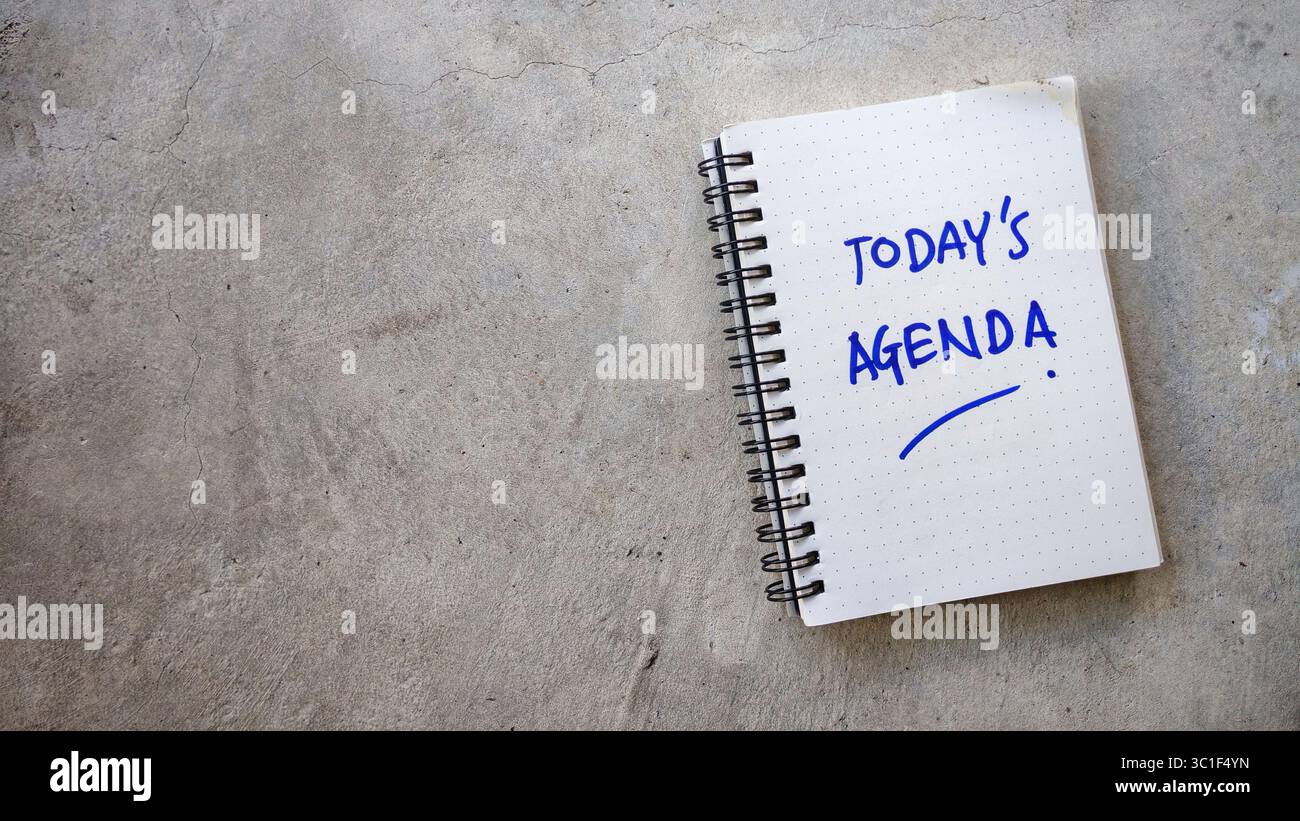 L'agenda di oggi è scritta a mano in un notebook Dot-Grid su uno sfondo di cemento incrinato Foto Stock