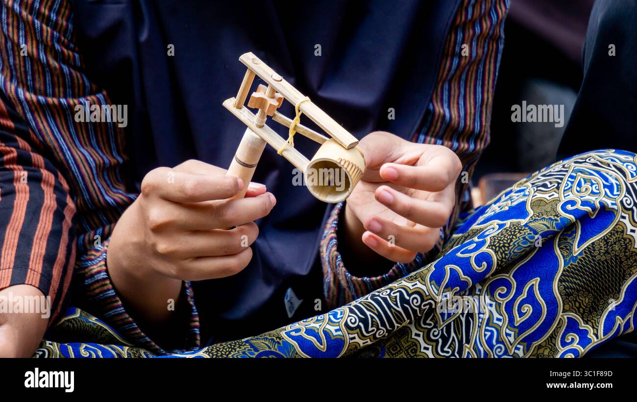 Giocare a giocattoli tradizionali (klotokan, otok-otok) in bambù. Il modo di giocare è girarlo Foto Stock