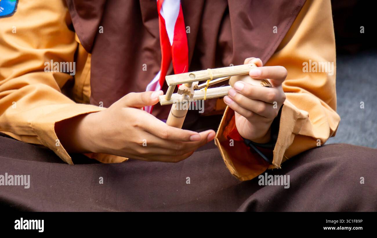 Giocare a giocattoli tradizionali (klotokan, otok-otok) in bambù. Il modo di giocare è girarlo Foto Stock