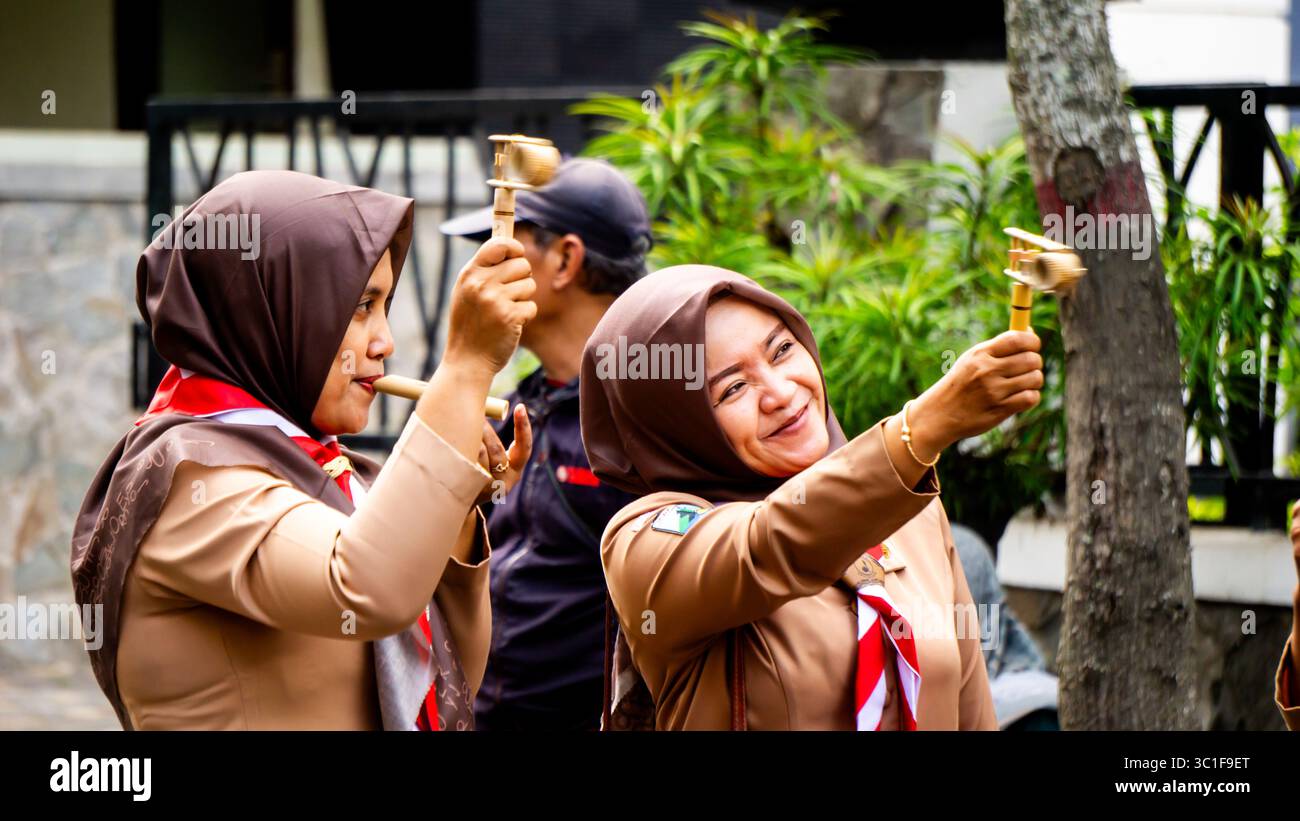 Giocare a giocattoli tradizionali (klotokan, otok-otok) in bambù. Il modo di giocare è girarlo Foto Stock