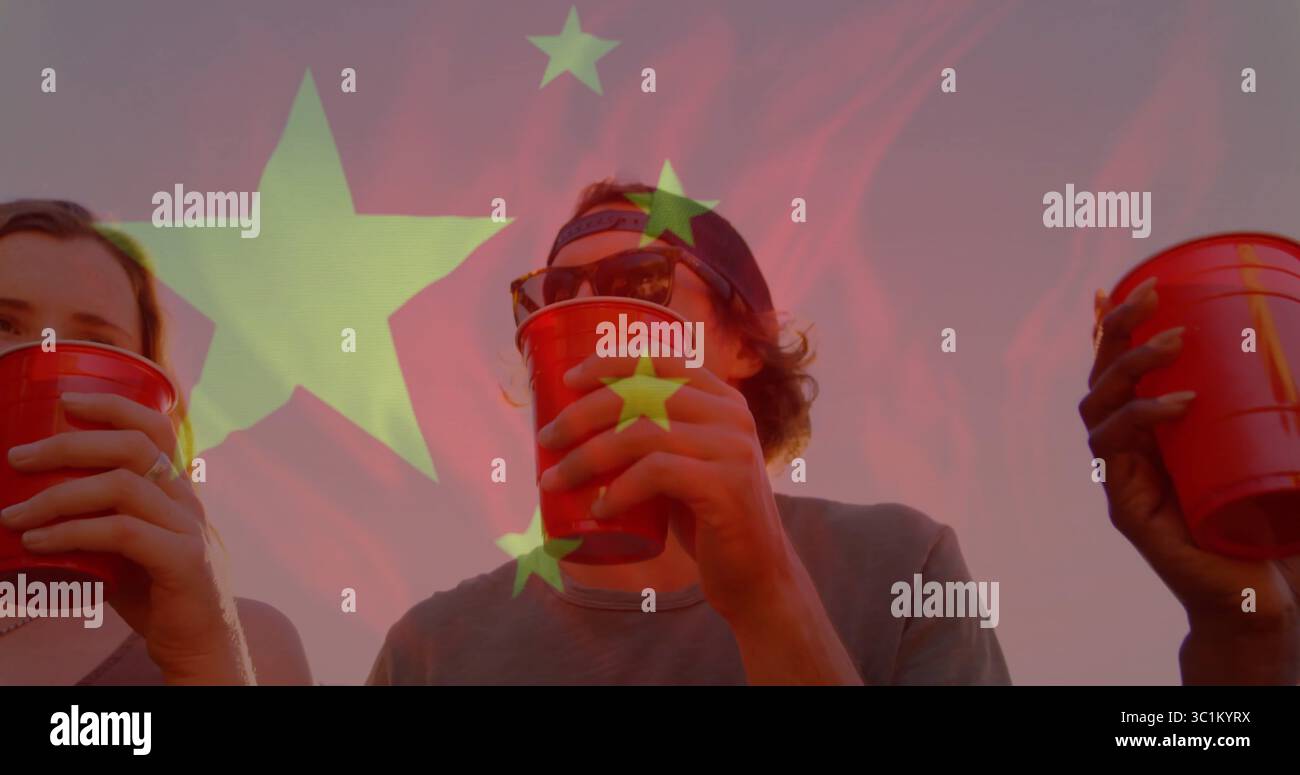 Sorseggiare gli amici indossando un berretto da baseball e occhiali da sole al tramonto, con coppe di plastica rosse Foto Stock