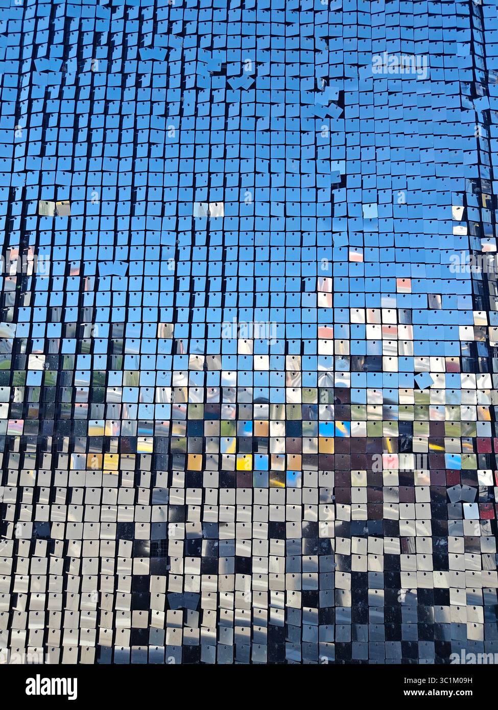Il mosaico di quadrati riflettenti crea un motivo colorato contro un cielo blu brillante, migliorando l'interesse visivo e la profondità Foto Stock