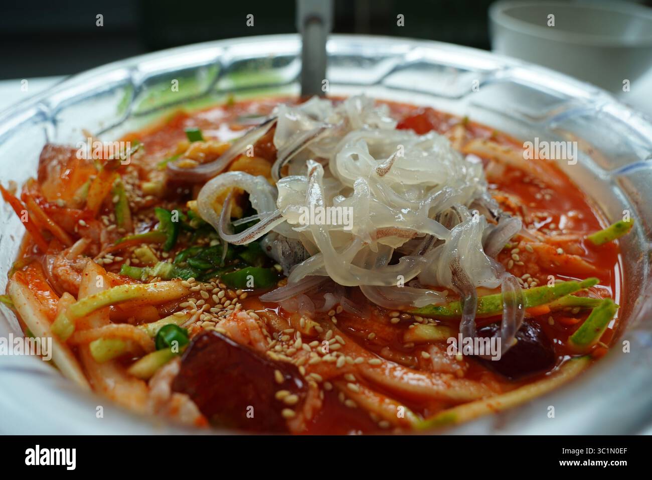 Zuppa fredda di spaghetti di pesce coreano piccante (Mulhoe) con sashimi di calamari freschi in una grande ciotola Foto Stock