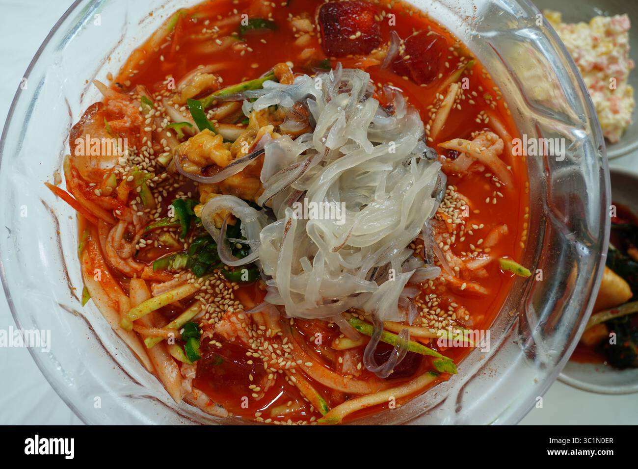 Zuppa fredda di spaghetti di pesce coreano piccante (Mulhoe) con sashimi di calamari freschi in una grande ciotola Foto Stock