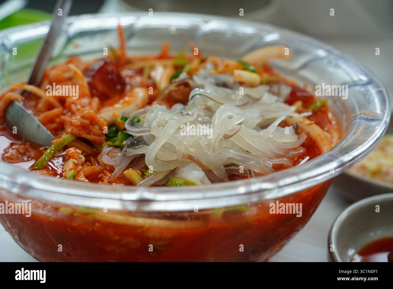 Zuppa fredda di spaghetti di pesce coreano piccante (Mulhoe) con sashimi di calamari freschi in una grande ciotola Foto Stock