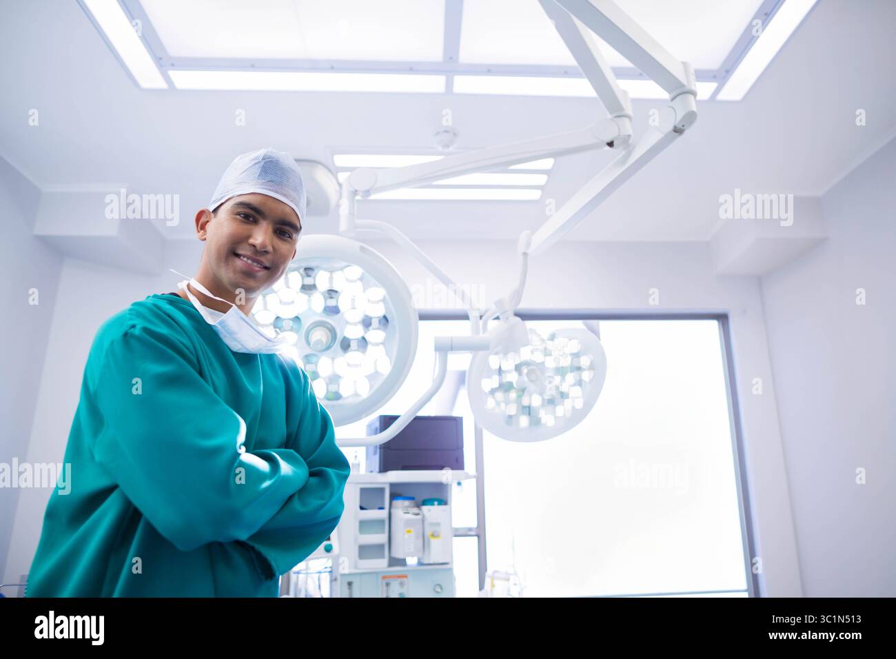Chirurgo maschile in piedi sotto le luci chirurgiche accanto alla macchina per anestesia in sala operatoria, spazio di copia Foto Stock