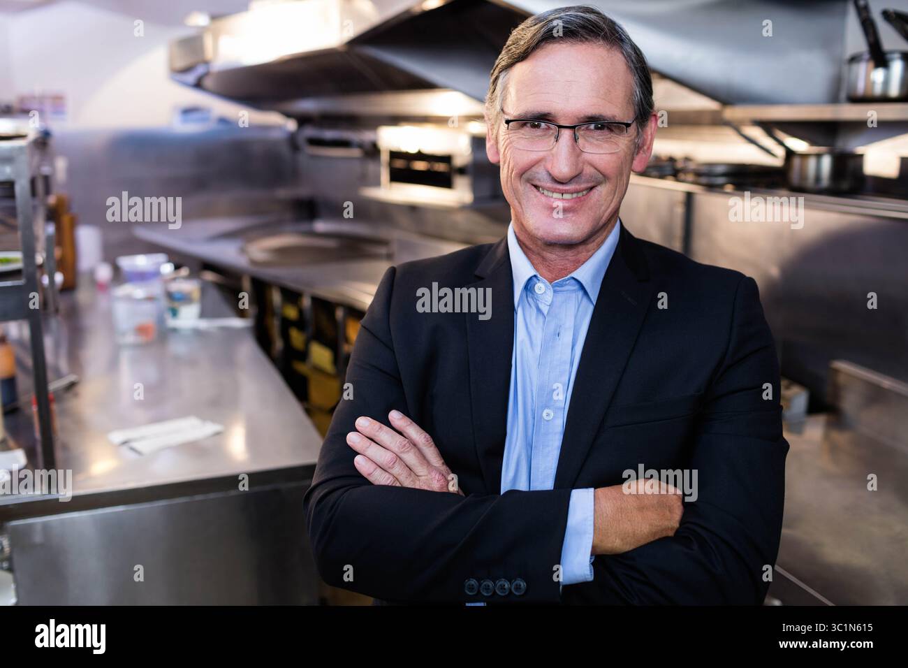 La cucina commerciale risplende sotto l'illuminazione diretta, con piano di preparazione in acciaio inox e vasetti per spezie Foto Stock