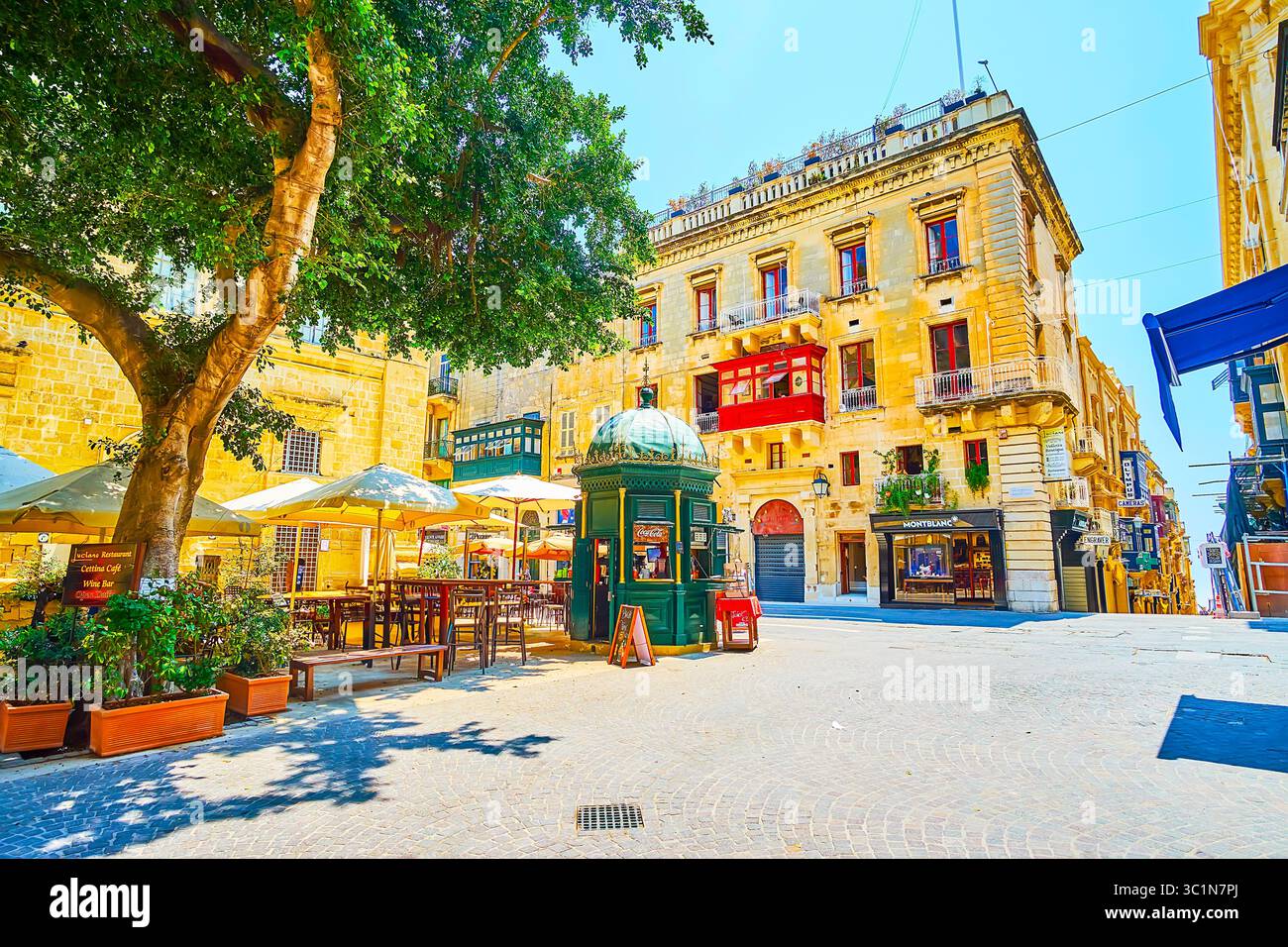 La Valletta, Malta - 19 giugno 2018: il San Giovanni square vanta un accogliente caffè all'aperto, nascosto nell'ombra degli alberi e ombrelloni e circondata dalla medioevale b Foto Stock