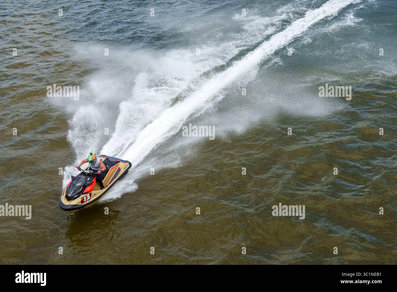 Una persona che indossa un casco e un equipaggiamento da corsa durante una gara d'acqua ad alta velocità Foto Stock