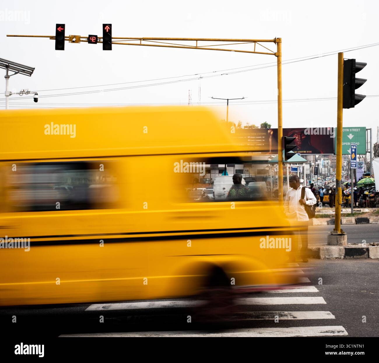 Lagos, Nigeria – 8 dicembre 2021: Il danfo giallo in movimento sfocatura supera un passaggio pedonale Foto Stock