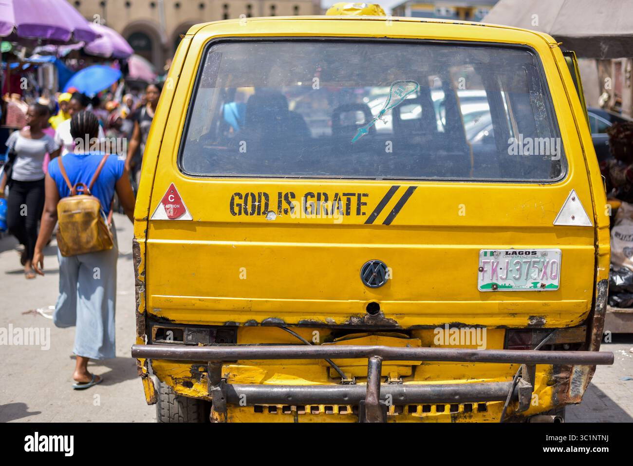 Lagos, Nigeria – 14 giugno 2022: Vista posteriore di un autobus danfo giallo con scritta "God is grate", parcheggiato in una vivace zona di mercato Foto Stock